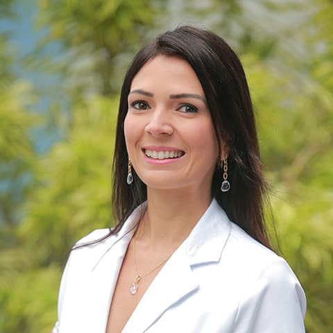Dra. Maíra Tavares, oncologista clínica, em retrato profissional de jaleco branco